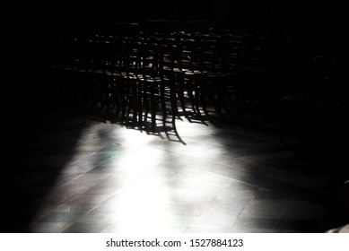 Empty Church Seats: Rows Of Chairs Are Bathed In Light And Shadows Within A Medieval Cathedral