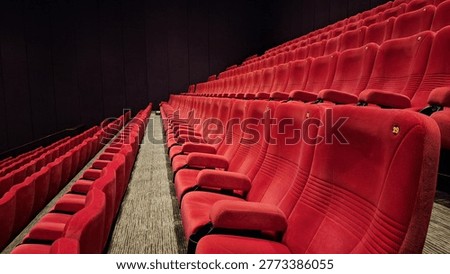 Empty cinema theater with rows of red seats in a dimly lit cinema building