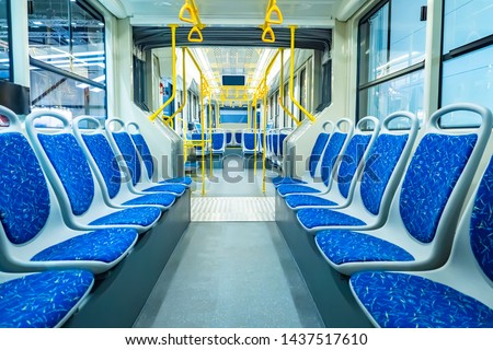 Empty city bus salon. Public land transport within the city. Seating for passengers. Handrails for holding. Contactless payment transport validators. Passenger urban transport.