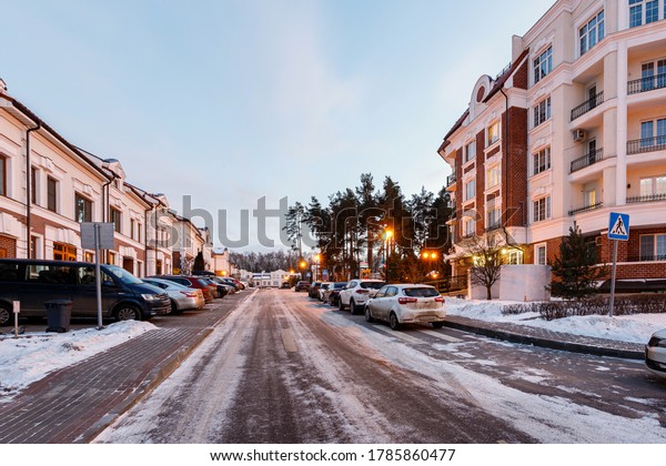 Empty\
city street, parked cars and road in snow in\
winter