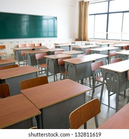 Empty classroom with chairs, desks and chalkboard.