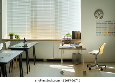 Empty Classroom During Break With Laptop And Other Supplies On Workplace Of Teacher And Two Desks Equipped With Microscope