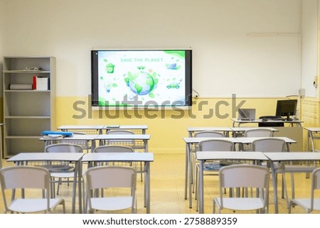 Empty classroom with an interactive whiteboard displaying a save the planet concept, promoting sustainability and modern education