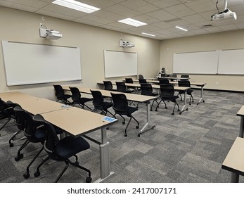 An empty classroom interior, with rows of desks and a projector suspended from the ceiling