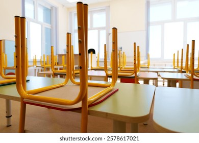 Empty classroom with overturned chairs and desks during midday in a bright and spacious setting