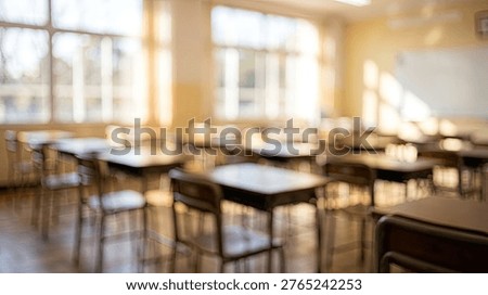 An empty classroom with rows of desks and chairs, illuminated by warm sunlight streaming through the windows.