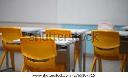 An empty classroom setting with rows of desks and vibrant orange chairs, suggesting a space ready for students and education.  Tangerang, Indonesia 8 April 2025