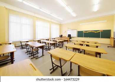 Empty classroom with wooden desks, chalk board and big windows in school. - Shutterstock ID 164473229