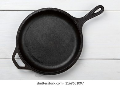 Empty, Clean Black Cast Iron Pan Or Dutch Oven Top View From Above On White Wooden Table