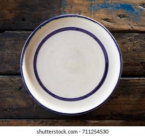 Empty Clean White Ceramic Plate With Blue Rim And Border Viewed From Overhead On Rustic Wood In Square Format