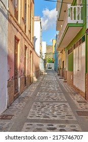 Empty Cobbled Street In A Rural European Tourist Town. A Quiet Narrow Alley Way With Colorful Apartment Buildings Or Houses. Hidden Side Street With Traditional Architecture In Santa Cruz De La Palma