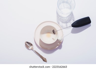 Empty Coffee Cup, Glass Of Water, Spoon And Black Milk Frother On White Table. Top View, Flat Lay.