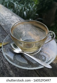 Empty Coffee Cup And Spoon  Which The Employees Have Not Yet Collected Are Placed On The Woods Table In The Green Garden.