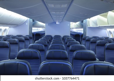 Empty commercial airplane cabin interior with blue leather seats. Two aisles and open overhead bins