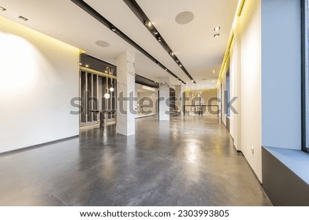 An empty commercial premises with polished concrete floors and installation of lights in the ceilings