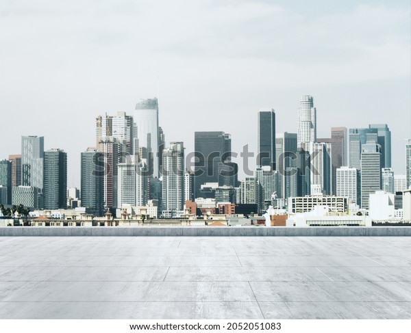 Empty concrete dirty\
rooftop on the background of a beautiful Los Angeles city skyline\
at daytime, mock up