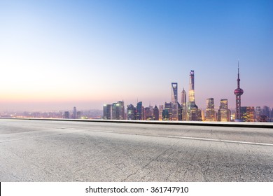 Empty Concrete Road And Cityscape In Blue Sky At Dawn