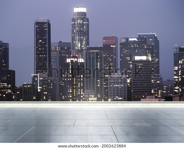 Empty concrete\
rooftop on the background of a beautiful blurry Los Angeles city\
skyline at twilight,\
mockup