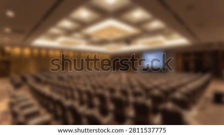 An empty conference hall with many rows of seats facing a projector screen, ready for an event.