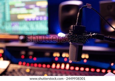 Empty control room with professional recording microphone and technical gear used for producing and editing music, sliders and buttons on panel board. Post production space. Close up.