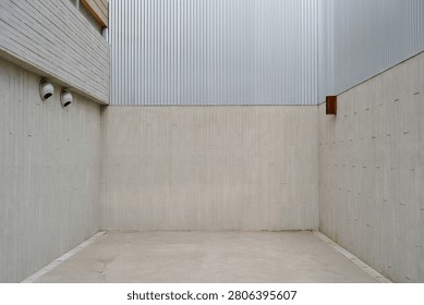 An empty corner featuring concrete and corrugated metal, creating a modern, stark, urban aesthetic