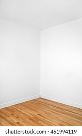 Empty Corner Of A Renovated Room With White Walls And Wooden Floor.