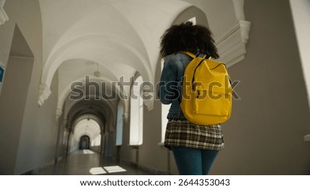 Empty corridor back view from behind student girl with yellow backpack follow going to class lesson in school university woman pupil female alone walking in academy college hall morning go to lecture