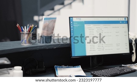 Empty counter with appointments forms on computer, health center reception front desk in medical clinic. Registration list on files and screen, clinical checkup examination in waiting room.