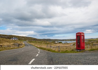 Empty Countryside Road In The Scottish Highlands With A Traditional British Red Telephone Box  On The Side