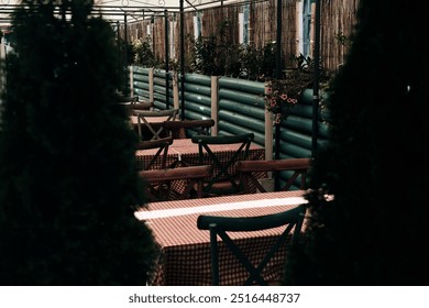 An empty cozy summer outdoor cafe in the center of Belgrade, Serbia. The restaurant has vintage wooden multicolored chairs and a red and white checkered tablecloth on the tables - Powered by Shutterstock