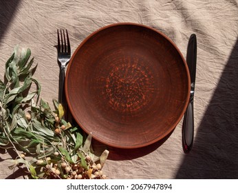 Empty craft handmade clay plate with fork knife linen tablecloth. Table place hand crafted dish. Natural cottagecore styled tableware minimal home interior decor. Restaurant food countryside aesthetic - Shutterstock ID 2067947894
