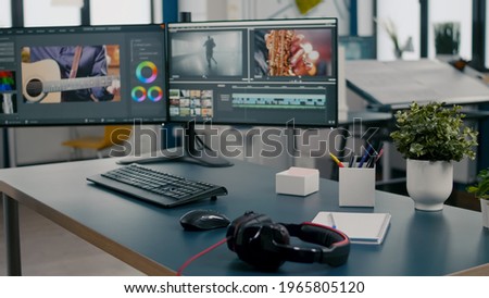 Empty creative multimedia studio with professional computer placed on desk, dual monitor setup. Video editing start up company agency with no people in it and post production software on pc displays