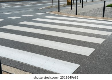 Empty crosswalk on a city street with striped white lines, indicating pedestrian crossing area. Concept of urban infrastructure, pedestrian safety, and road design. High quality photo - Powered by Shutterstock