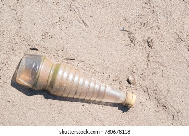 Empty crumpled plastic bottle of water abandoned on the beach