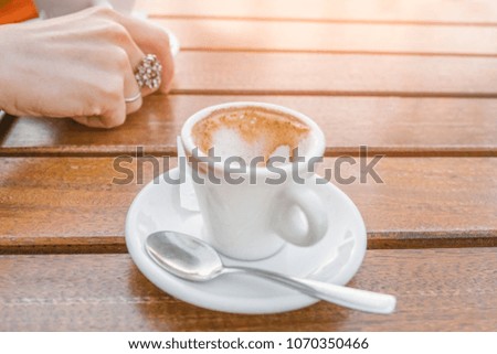 empty cup of coffee on a table near a woman's hand