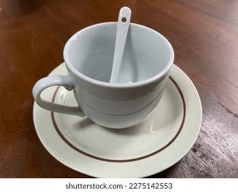 an empty cup complete with a spoon on the table