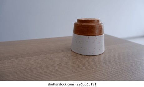 The empty cup lay face down on the wooden table. Cup for tea or coffee. Ceramic cup. Ceramic artwork.