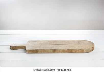 Empty Cutting Board For Cheese On White Wooden Table.