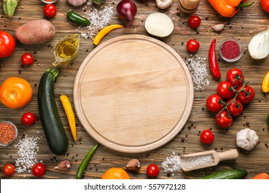 Empty cutting board and vegetables on wooden background