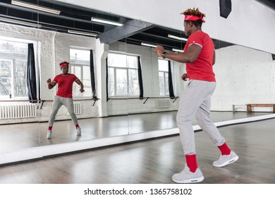 Empty dancing studio. Positive hard-working young man being in great mood while spending time alone