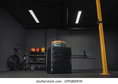 Empty Dark Crossfit Gym. Professional Sports Equipment For Workout, Weightlifting, Powerlifting, Fitness, Crossfit. Jumping Box, Weights, Airbike. Copy Space