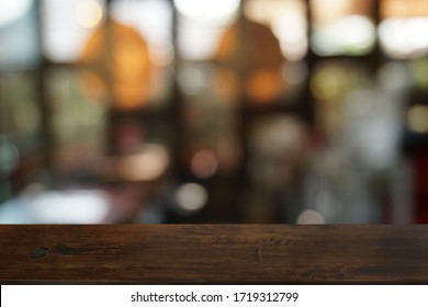 Leer dunkler Holztisch vor abstraktem, unscharfem Bokeh-Hintergrund des Restaurants . kann für die Anzeige oder Montage Ihrer Produkte verwendet werden.Mock up for space.