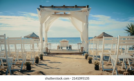 Empty Decorated Outdoors Wedding Venue with Chairs for Official Ceremony on a Beach Near the Sea or Ocean. Everything Prepared for Beautiful Romantic Marriage Celebrations. Guests are Arriving Soon. - Powered by Shutterstock