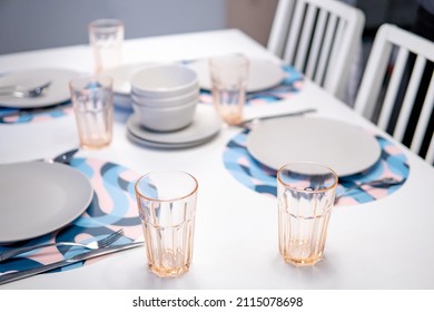 Empty dinner set on modern white dining table. Group of plate, bowl, glass and cutlery