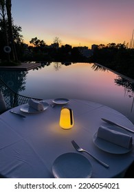 Empty dinner table next to the pool with sky sunset