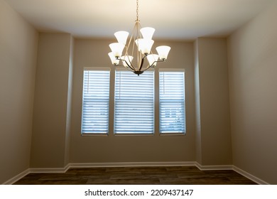 Empty Dinning Room In An Apartment With Ceiling Chandelier And Window.