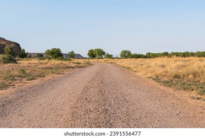 An empty dirt road bends out of sight near red rock mesas in the high desert countryside. - Powered by Shutterstock