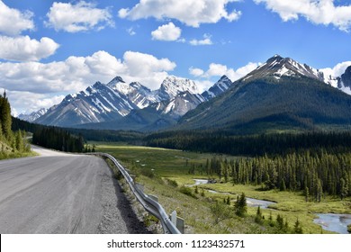 Empty dirt road through snow capped mountains in the Canadian Rockies - Powered by Shutterstock