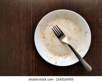 Empty Dirty White Plate With Fork On Brown Wood Table With Copy Space.