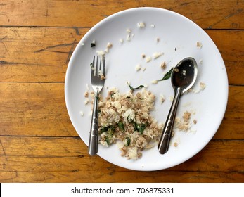 Empty Dish With Spoon And Fork After Eating On The Wooden Table. Top View Of Empty Plate, Dirty After The Meal Is Finished